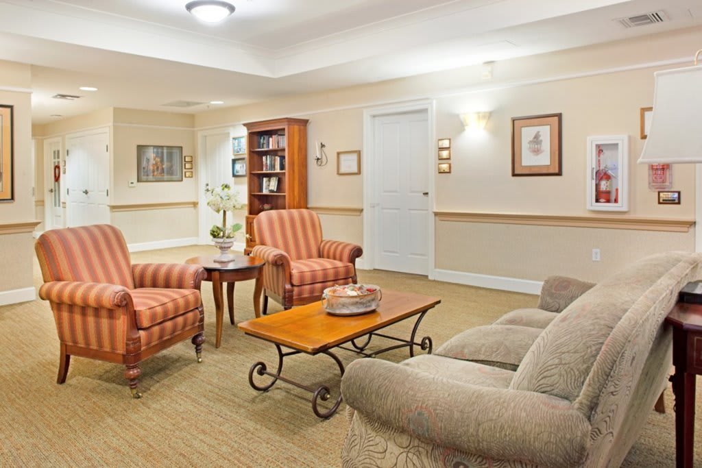 A cozy living room with armchairs, a sofa, and a coffee table surrounded by artwork and a bookshelf.