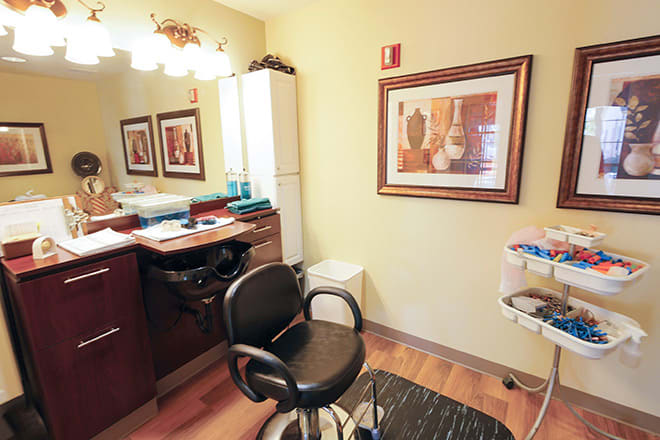 A cozy hair salon interior featuring a styling chair, mirror, and wall art.