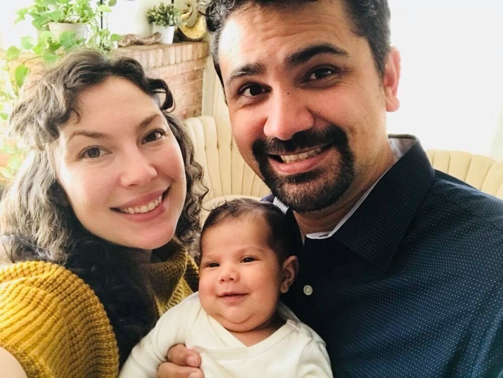 A happy family posing for a photo with their baby.