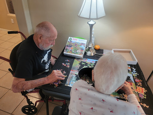 An elderly couple enjoying a peaceful afternoon working on a puzzle together.