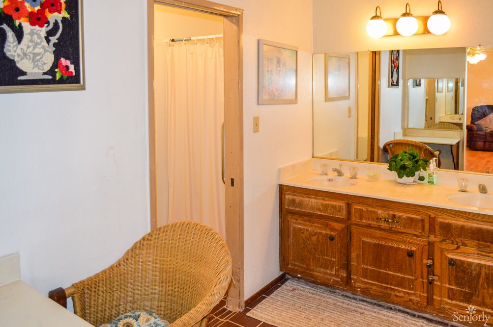 A cozy bathroom with a wooden vanity and wicker chair.