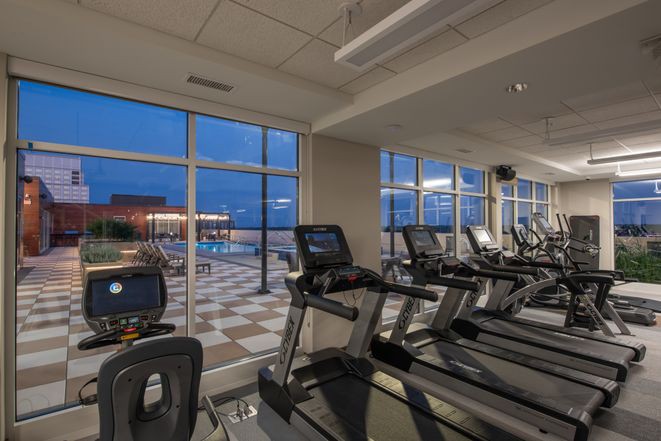 A modern gym with treadmills and a scenic night view through large windows.