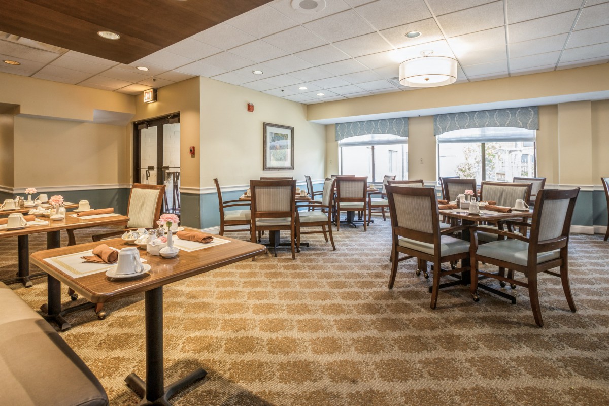A well-lit dining area with neatly arranged tables and chairs, featuring a cozy interior design.