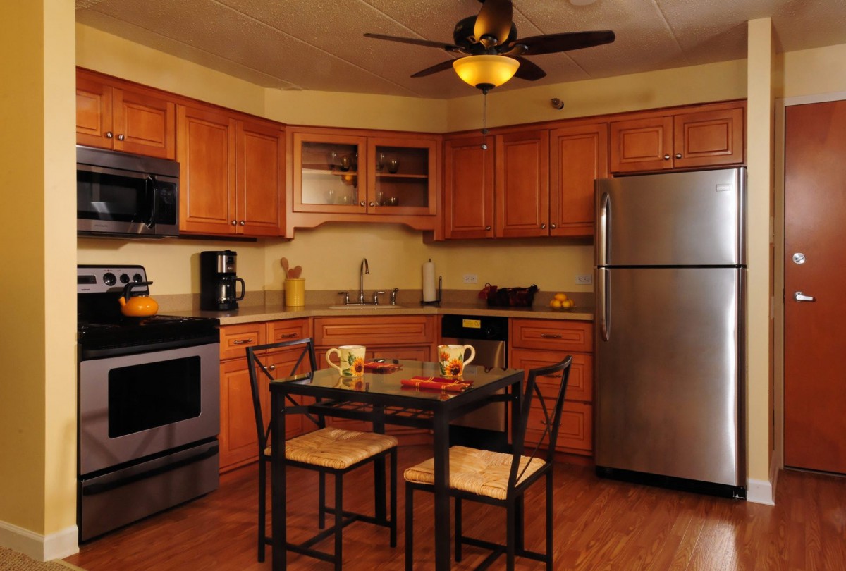 A modern kitchen with wooden cabinets, stainless steel appliances, and a small dining table.