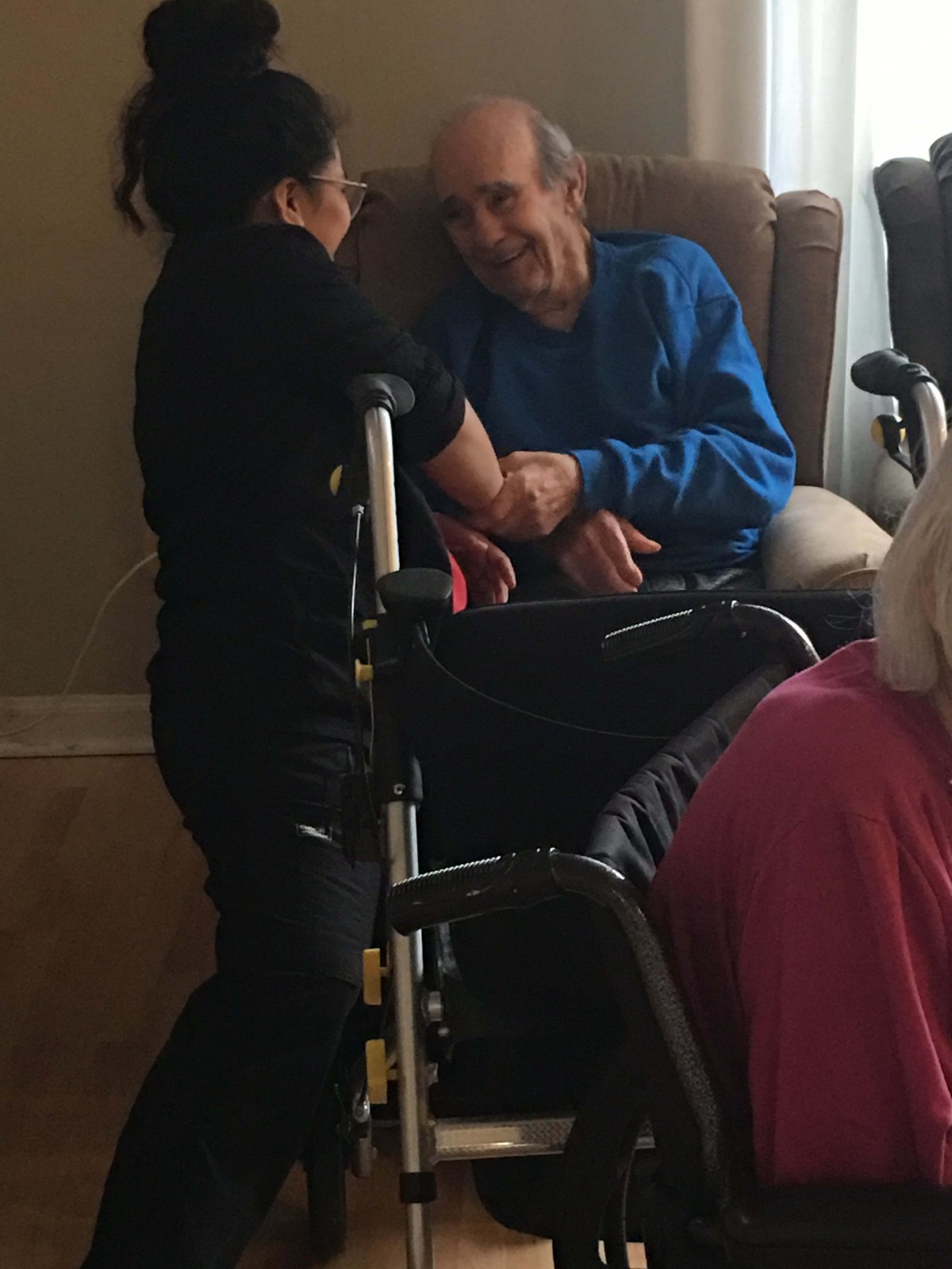 A caregiver interacting with an elderly person in a wheelchair.