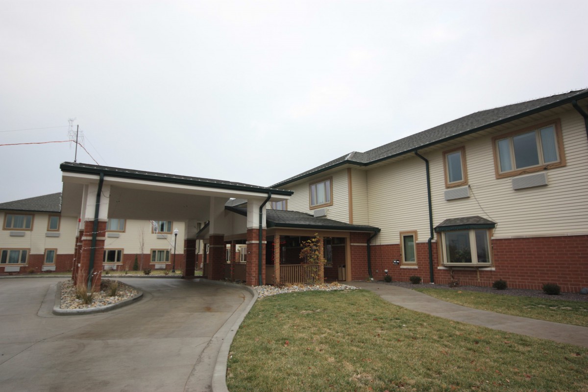 A two-story residential building with a covered entrance and driveway.