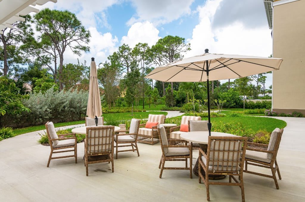 A spacious outdoor patio area with comfortable seating and umbrellas, surrounded by lush greenery.