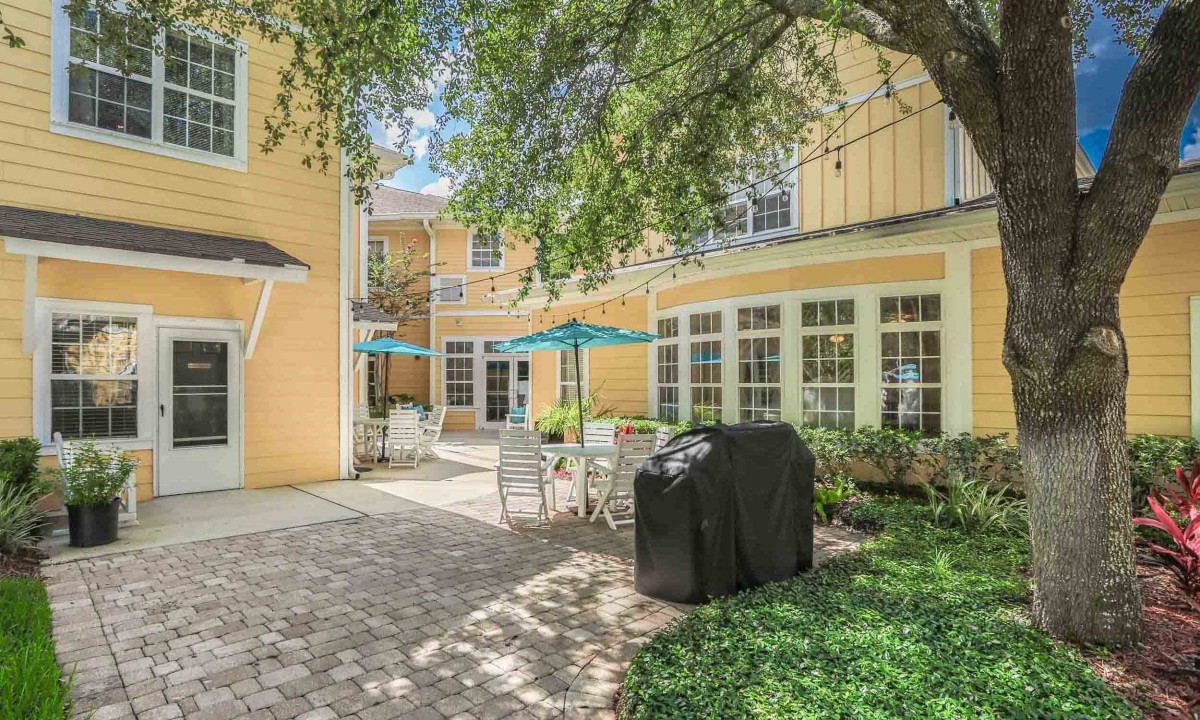 A cozy outdoor patio area with tables, chairs, and umbrellas next to a building.