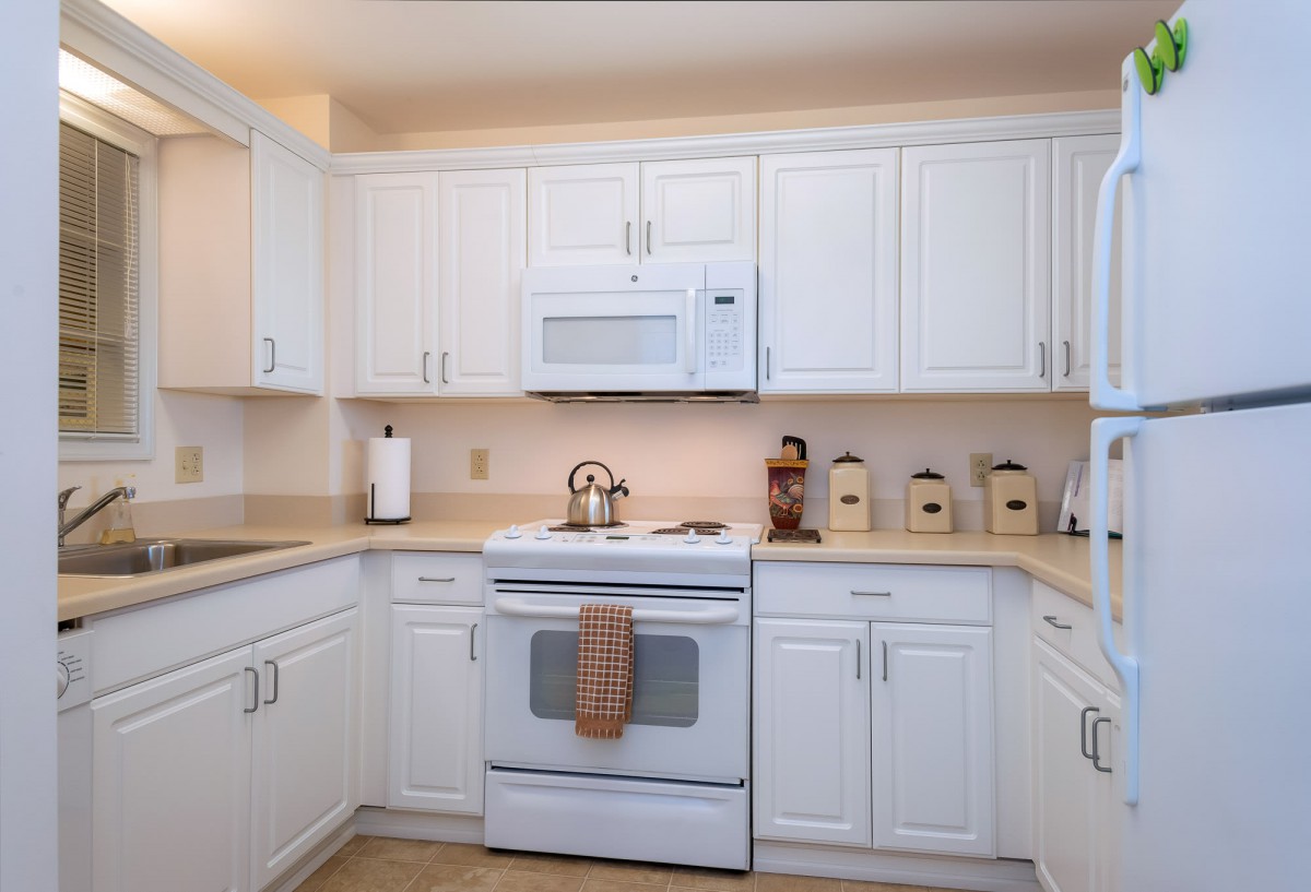 A modern kitchen with white cabinets and appliances.
