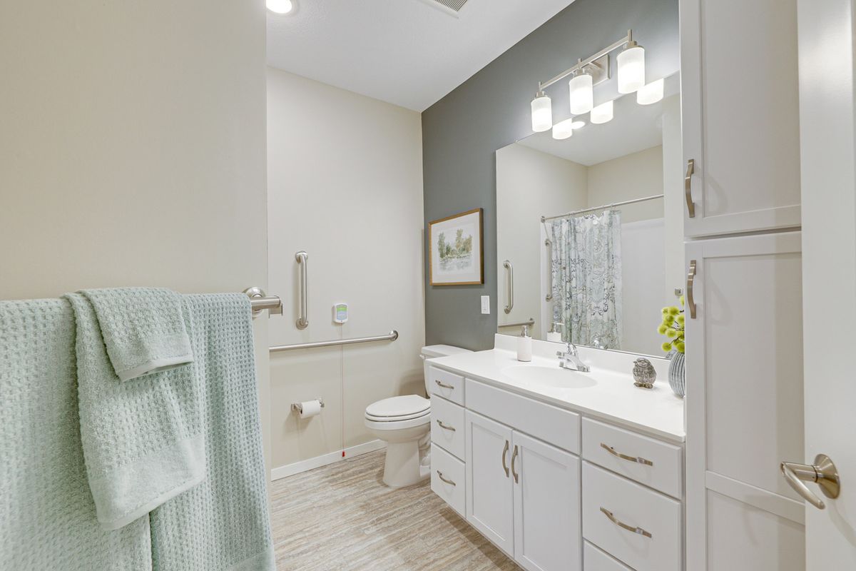 A modern bathroom interior featuring a large mirror, dual sinks, and contemporary lighting.