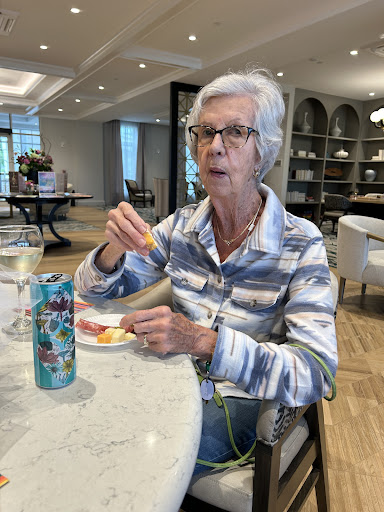 An elderly woman enjoying her meal and drink in a cozy dining setting.