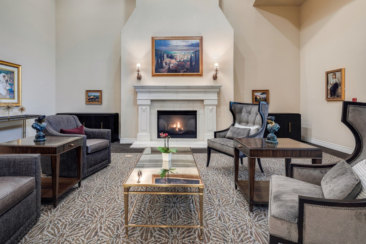 A cozy and elegant living room featuring a fireplace, artwork, and comfortable seating.