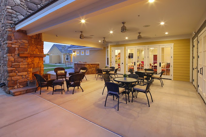 A cozy outdoor patio area with tables and chairs under warm lighting, offering a comfortable space for dining or gatherings.