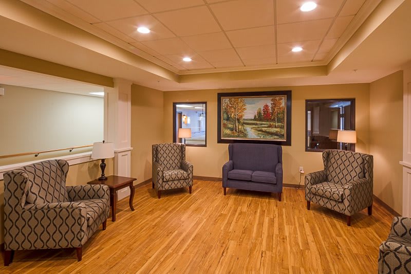A cozy seating area with armchairs and a sofa, featuring a landscape painting on the wall.