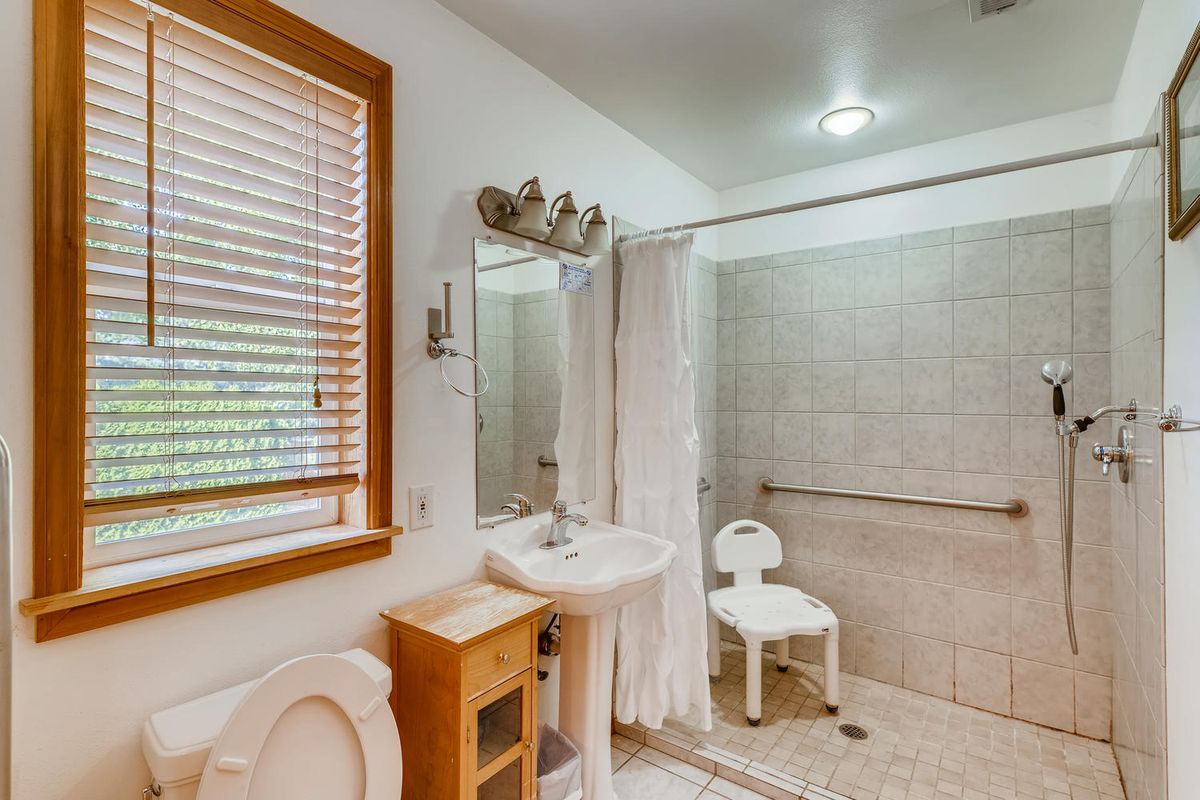 A well-equipped accessible bathroom with a shower chair and tiled walls.