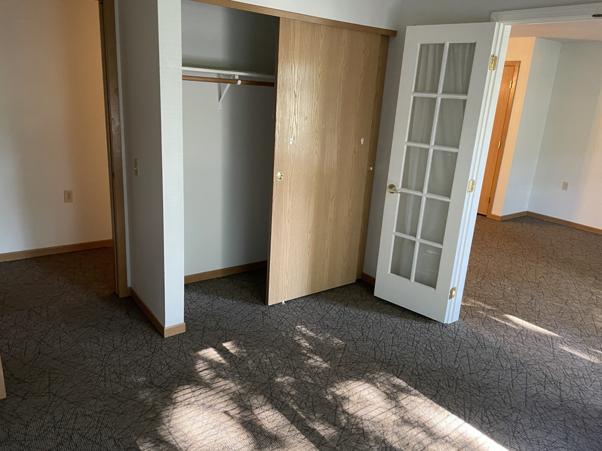 An empty room with a closet and sunlight filtering through the window.