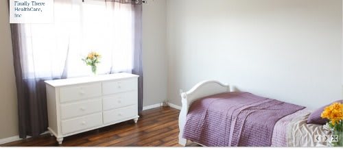 A minimalist bedroom with a white dresser, single bed, and hardwood flooring.