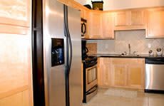 A modern kitchen featuring stainless steel appliances and light wood cabinets.