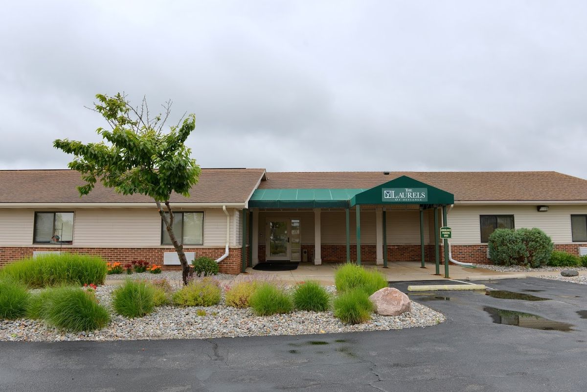A building with a green awning and landscaped surroundings on an overcast day.
