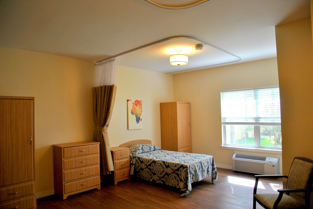 A minimalist bedroom with a single bed, wooden furniture, and a window providing natural light.