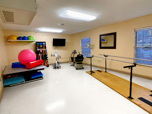 A well-equipped physical therapy room featuring various exercise equipment and a barre for rehabilitation exercises.