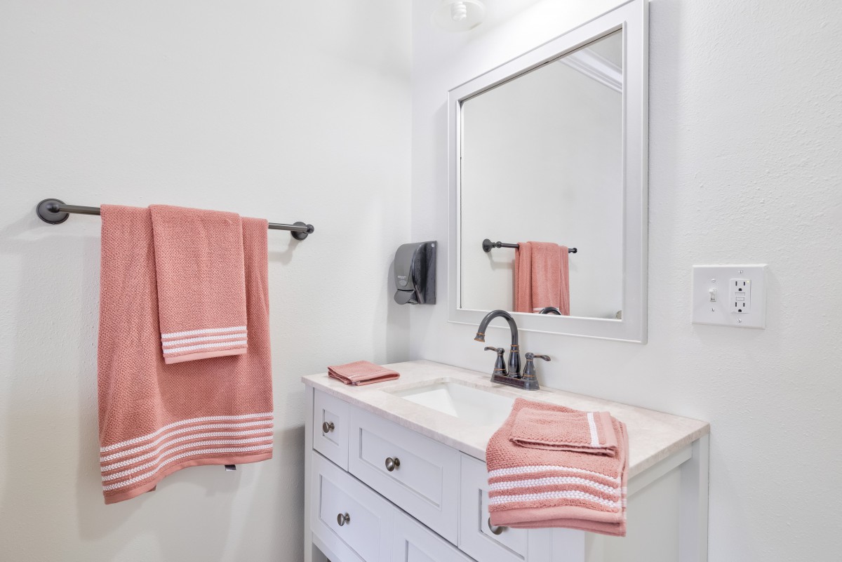 A tidy bathroom with pink towels and a large mirror above the sink.
