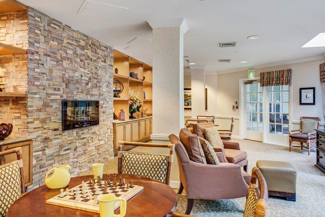 A cozy living room with comfortable seating, a stone wall, and a chess board on the table.