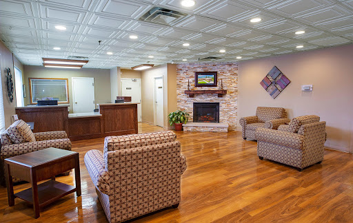 A cozy and inviting lobby area featuring comfortable seating, a fireplace, and a warm wooden floor.