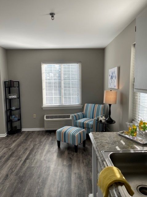A modern living room with a striped armchair and ottoman, featuring gray walls and wooden flooring.
