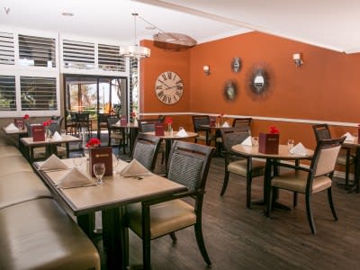 A cozy restaurant interior with neatly arranged tables and chairs against warm orange walls.