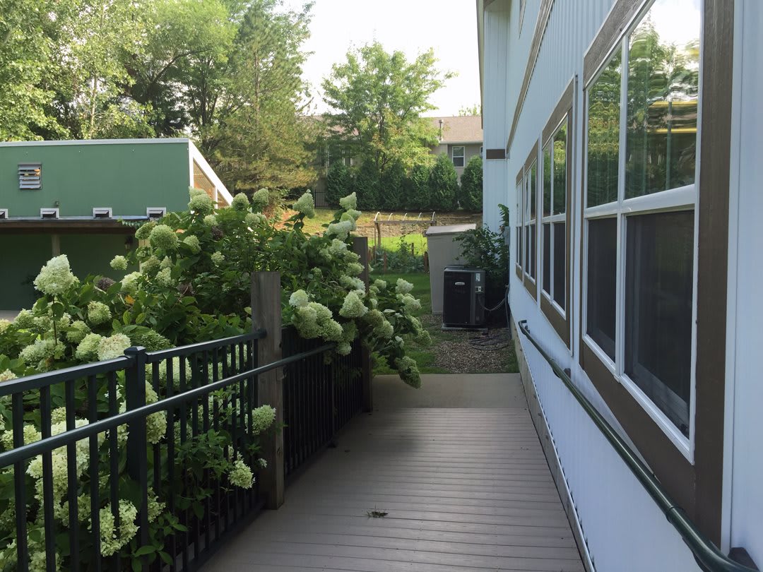 A scenic pathway alongside a building lined with lush greenery and blooming plants.