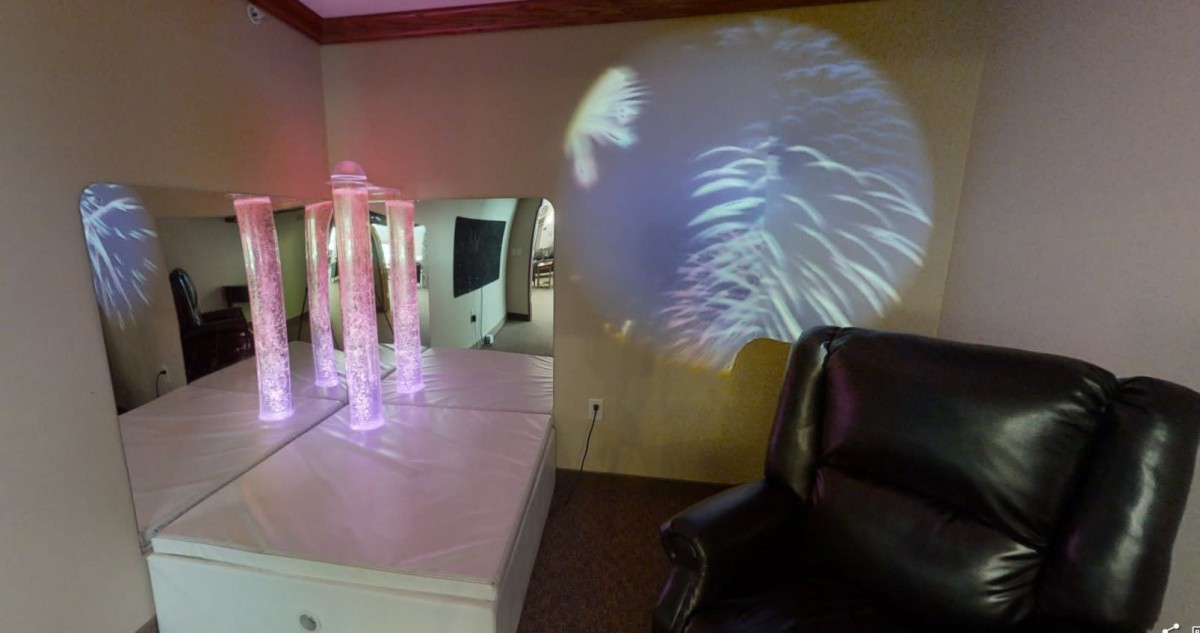 A room with a modern interior featuring mirrored surfaces and a light projection on the wall.