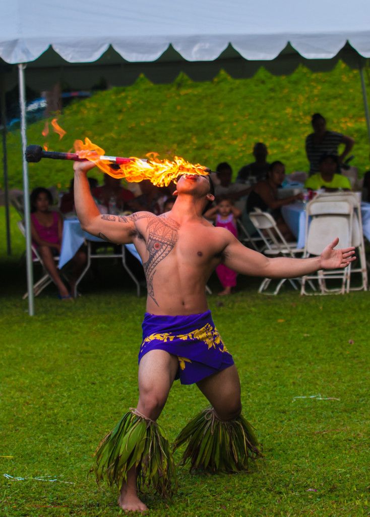 A performer skillfully eats fire during a vibrant outdoor cultural event.