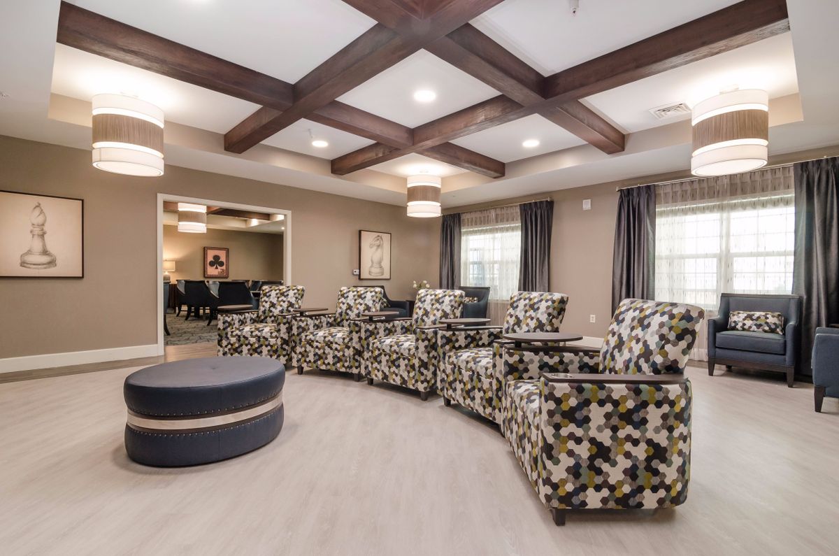 A modern lounge area with patterned armchairs and stylish ceiling beams.