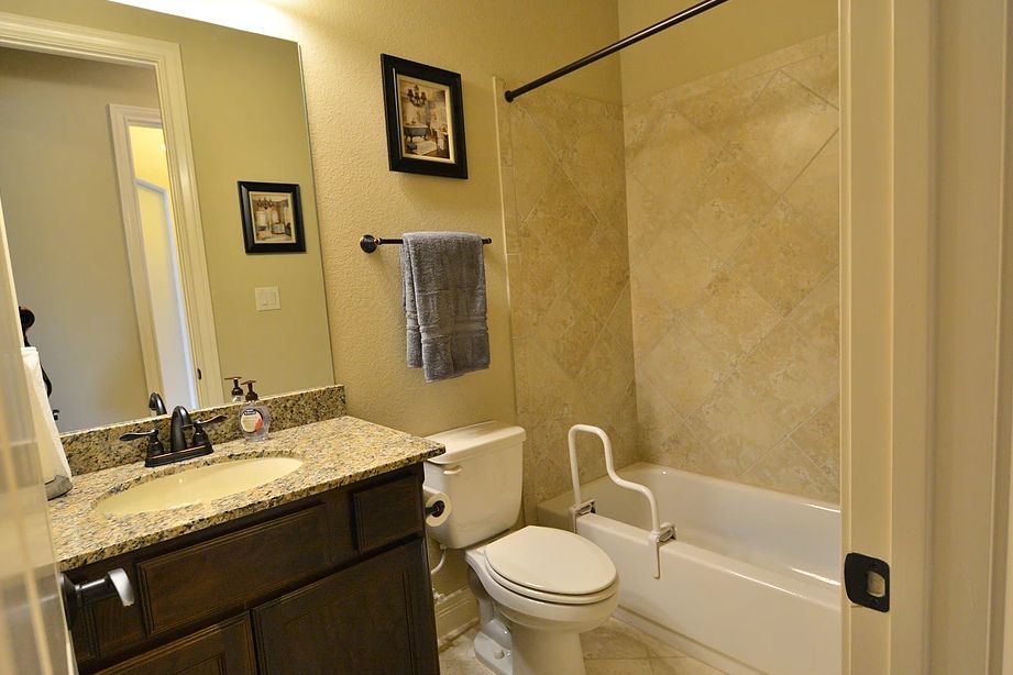 A well-appointed bathroom featuring a bathtub with a grab bar, a toilet, a sink with countertop space, and decorative elements like framed pictures and a towel rack.