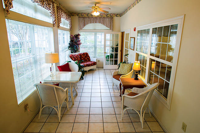 A cozy sunroom with comfortable seating and large windows.