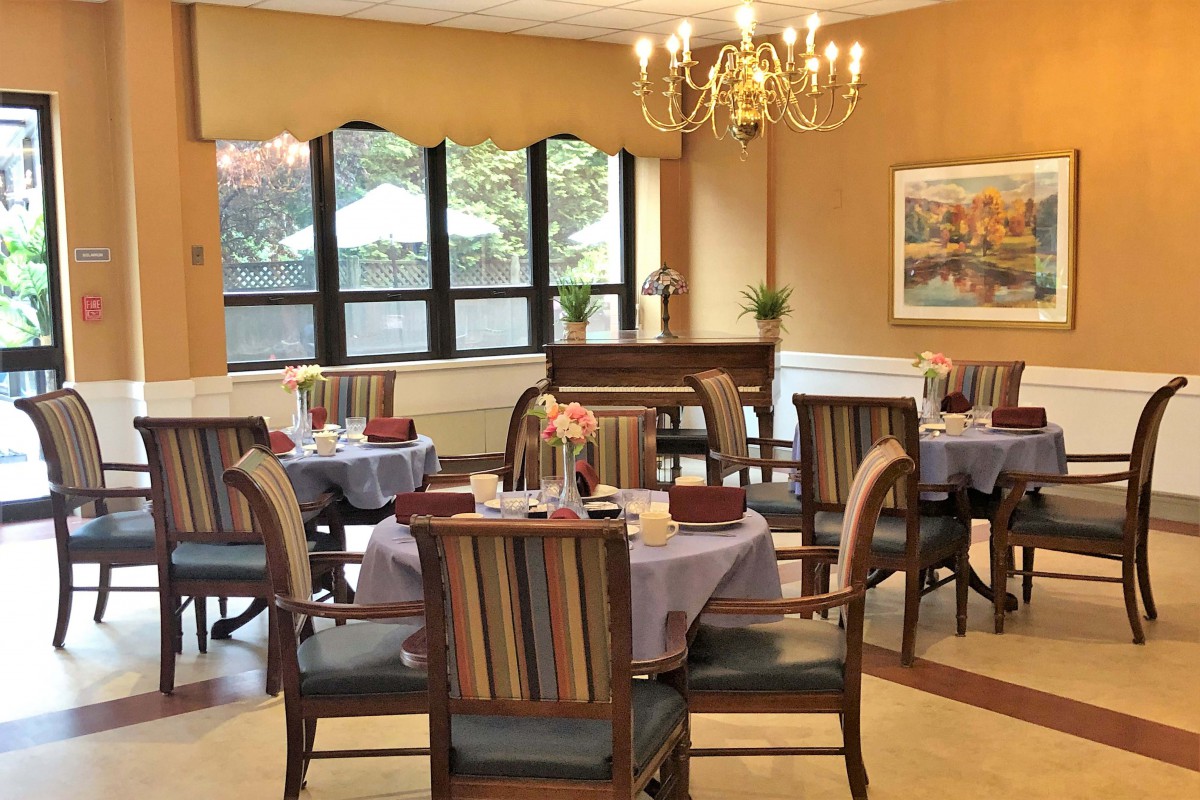 A cozy dining room with elegantly set tables and a chandelier.