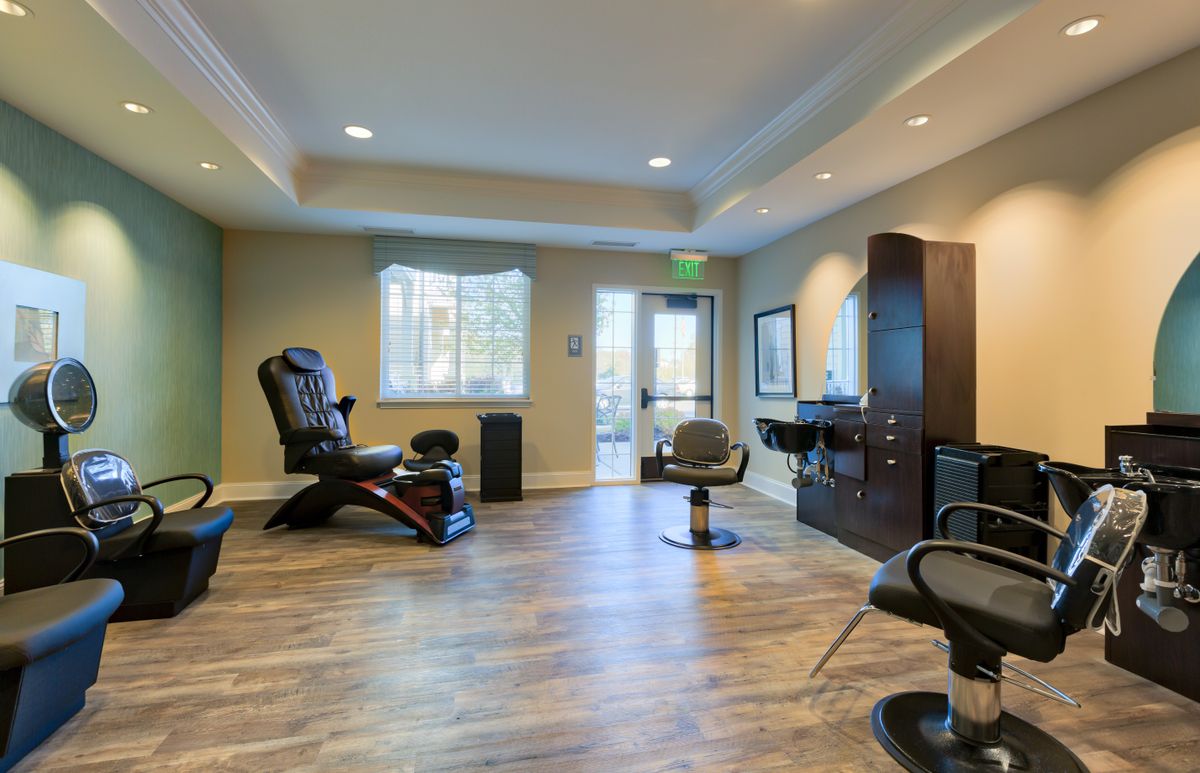 A modern salon interior with various chairs and styling stations.