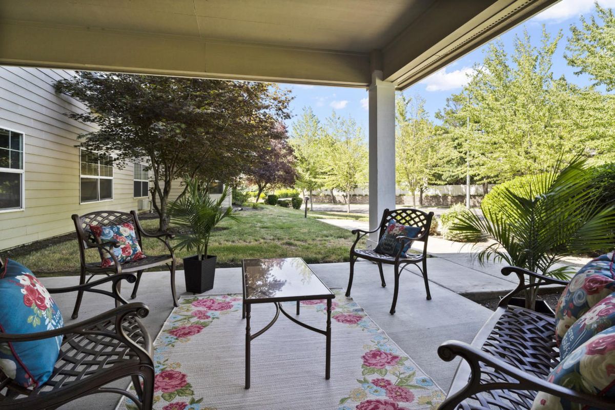 A cozy patio with outdoor seating surrounded by a lush garden.
