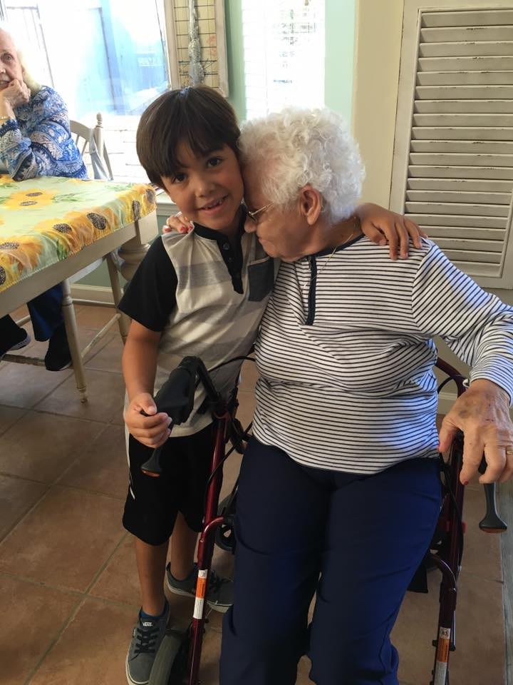 A young boy hugs his grandmother who is seated in a wheelchair, sharing a moment of love and bonding.