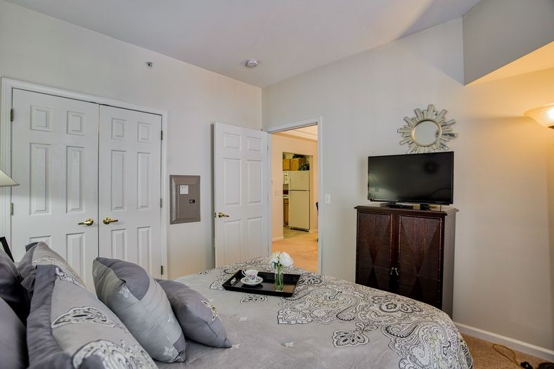 A cozy bedroom featuring a neatly made bed, TV on a dresser, and stylish decor.