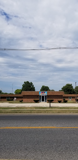 A view of a brick building surrounded by greenery under a cloudy sky.