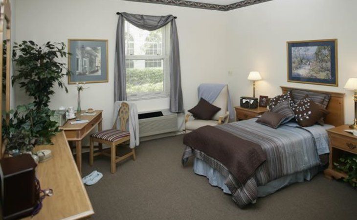 A cozy bedroom with a bed, desk, and chair next to a window.