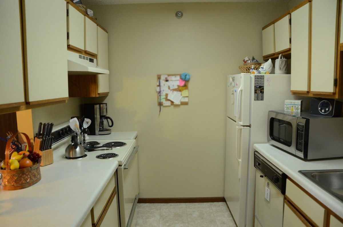 A compact kitchen with essential appliances, including a fridge, microwave, and coffee maker.