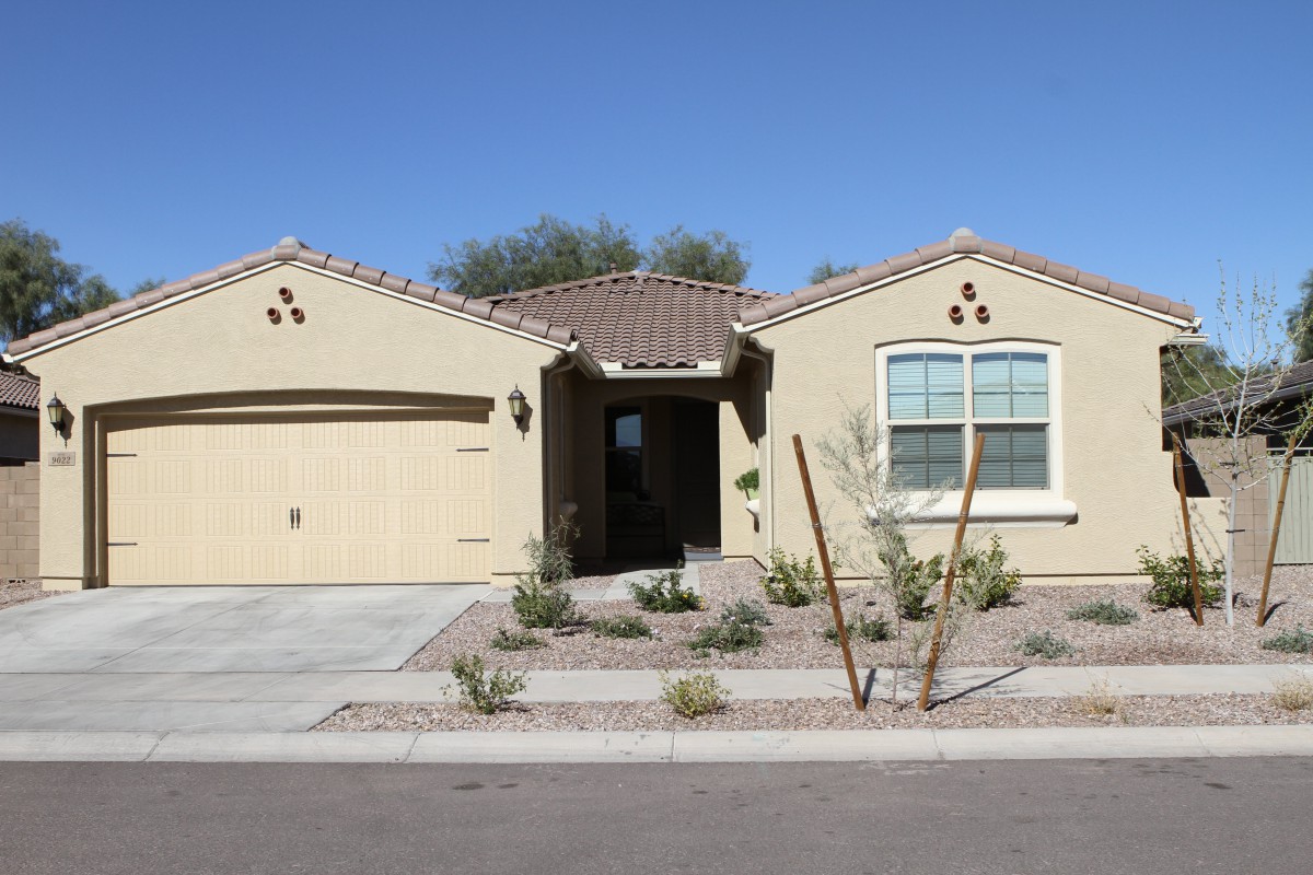 A single-story suburban house with a desert landscape front yard.