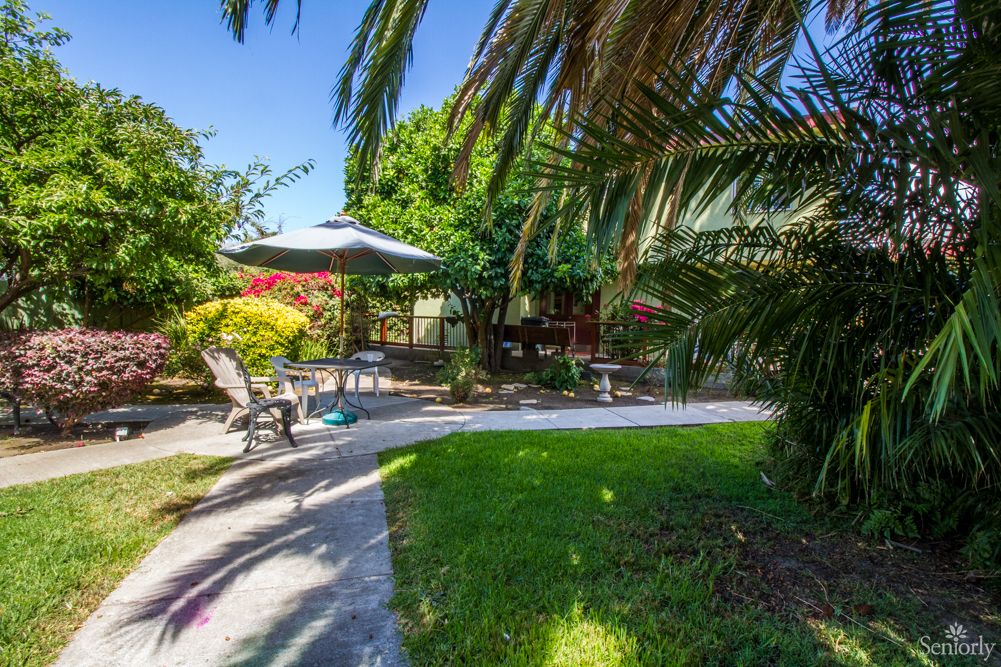 A tranquil garden setting with patio seating and umbrella.