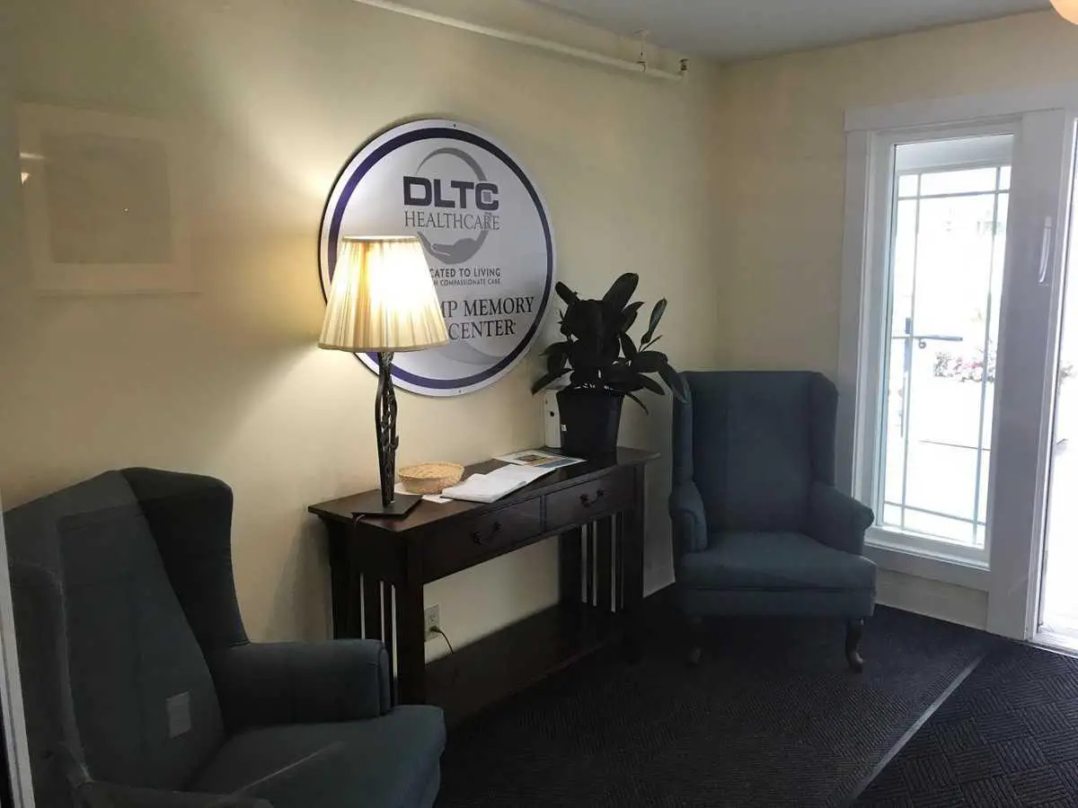 A cozy office waiting area with chairs, a lamp, and a sign on the wall.