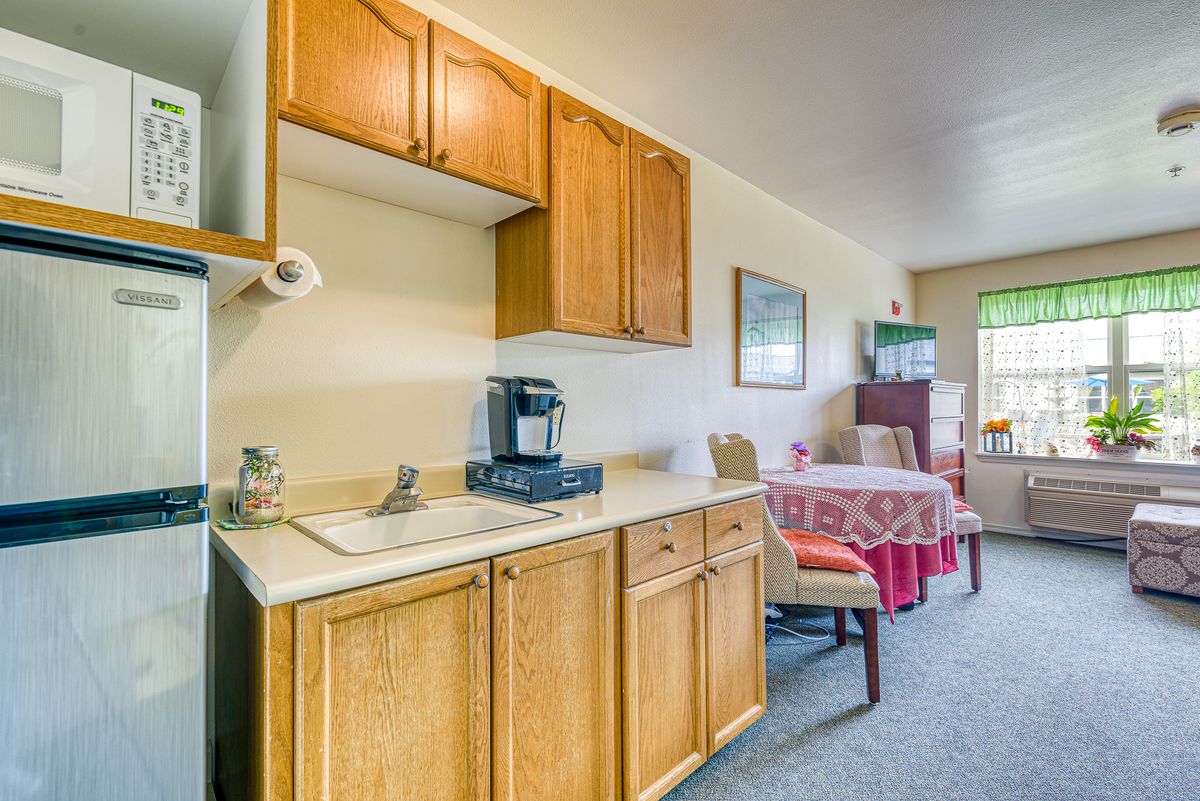 A cozy kitchen and dining area with wooden cabinets and a coffee maker.