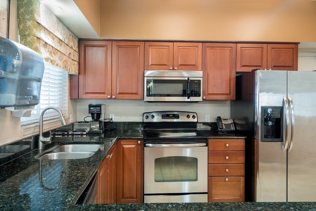 A modern kitchen featuring stainless steel appliances, wooden cabinets, and granite countertops.