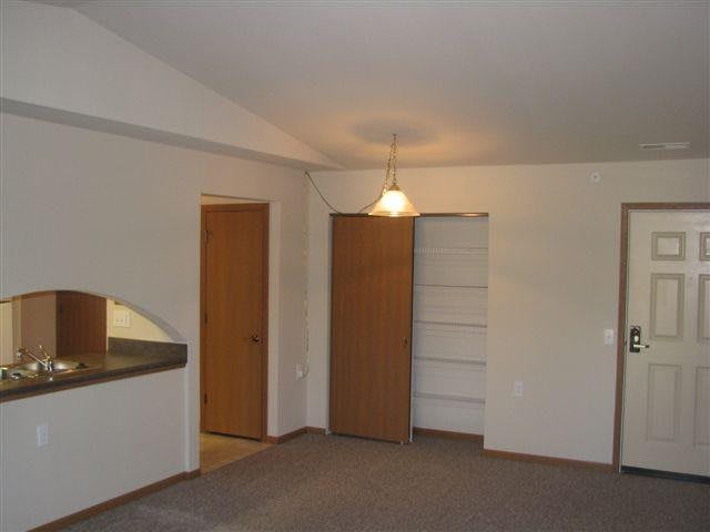 An empty room with a light fixture, closet, and doorway.